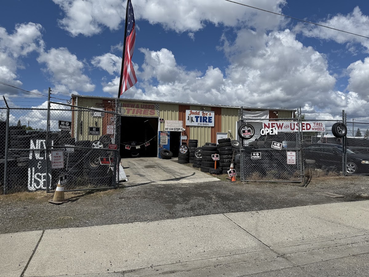 The Judd Lee's Tire shop front in daylight, flag flying, open for business