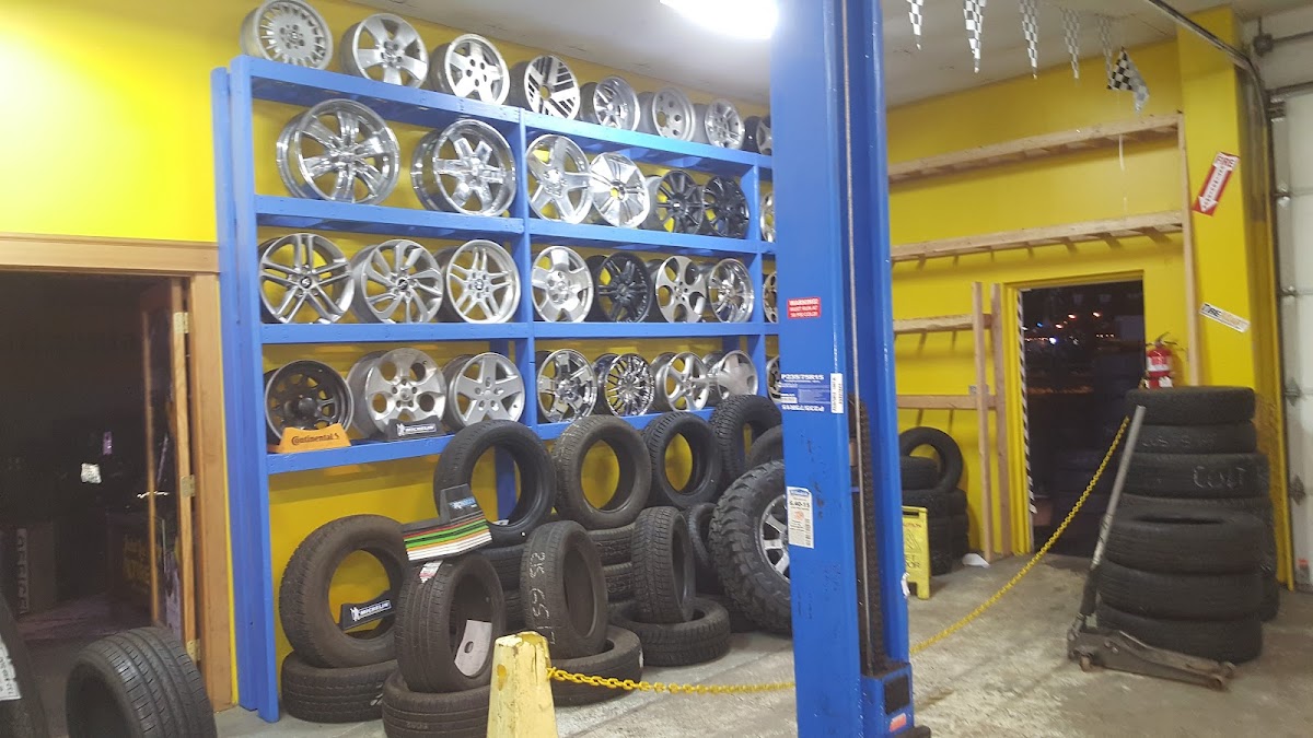 Wall of alloy wheels and stacked tires inside Judd Lee's Tire